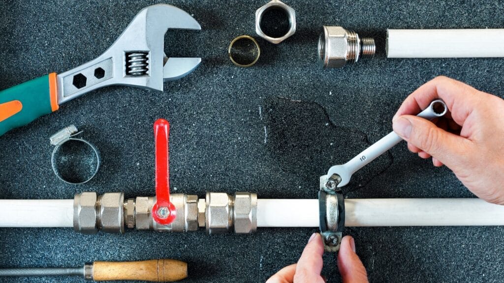 Plumber repairing a pipe valve with an adjustable wrench in Tarpon Springs