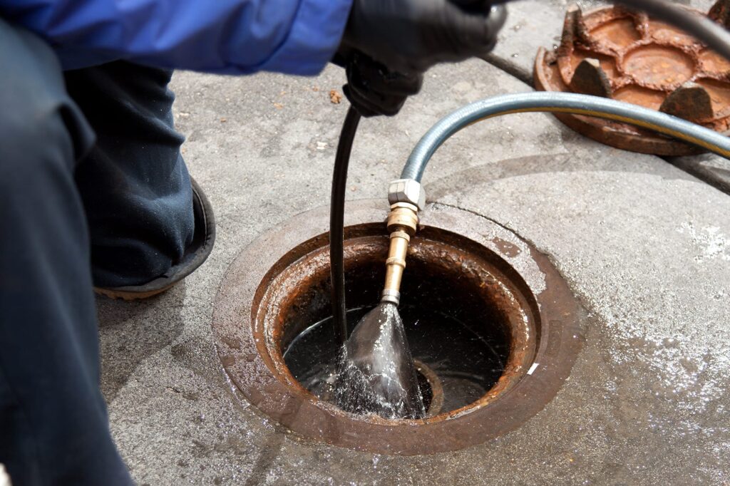 Plumber hydro jetting a sewer line through a manhole in Tarpon Springs