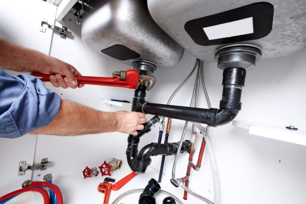 Plumber repairing drain pipes beneath a kitchen sink in Tarpon Springs