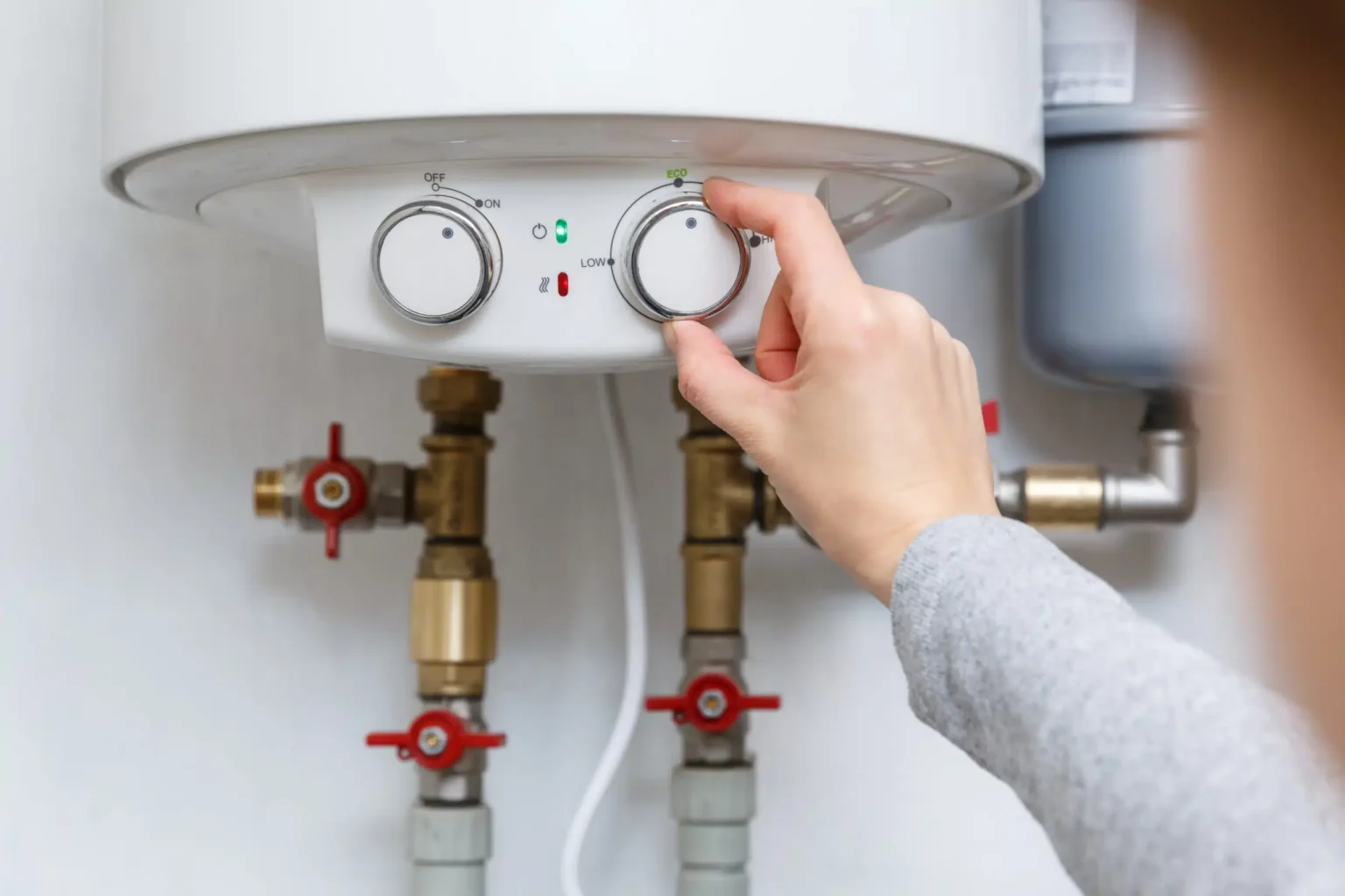 Homeowner adjusting the temperature controls on a water heater in Tarpon Springs